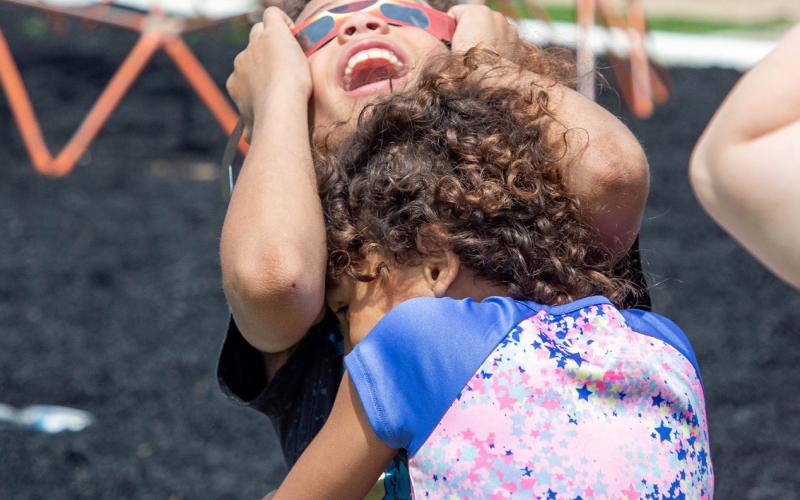 The Boys &amp; Girls Club had an eclipse viewing party and Beckham St. Clair gazes skyward at the eclipse while being embraced by Lyllian Richardson. Matt Swearengin | Durant Democrat
