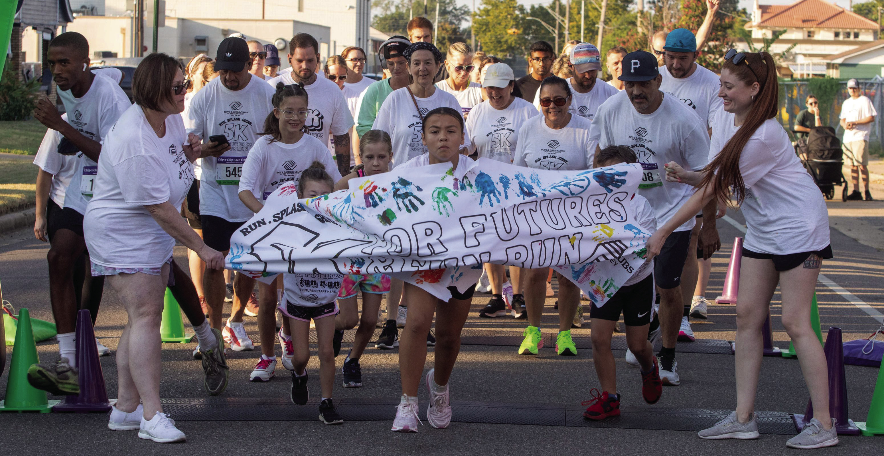 Runners during the Boys &amp; Girls Club Color Run crash through a paper banner at the start of the race Saturday morning. Matt Swearengin | Durant Democrat