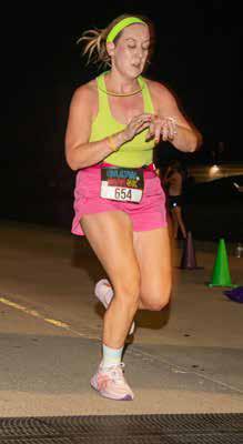 Spencer Harvey checks her time as she crosses the finish line during the Feedling Hope 5K run Friday evening.