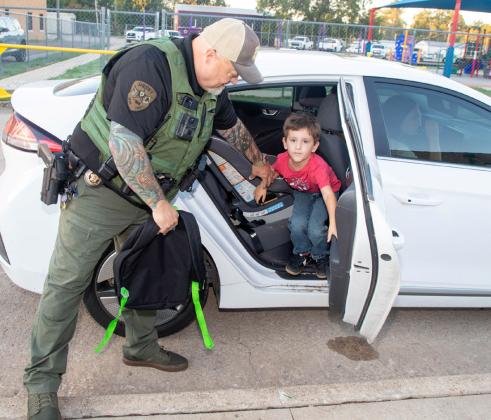 Bryan County Sheriff’s Deputy Scott Brown helps Robert E. Lee Early Childhood Center student Atlas Johnson out of the car for the start of school. Matt Swearengin | Durant Democrat