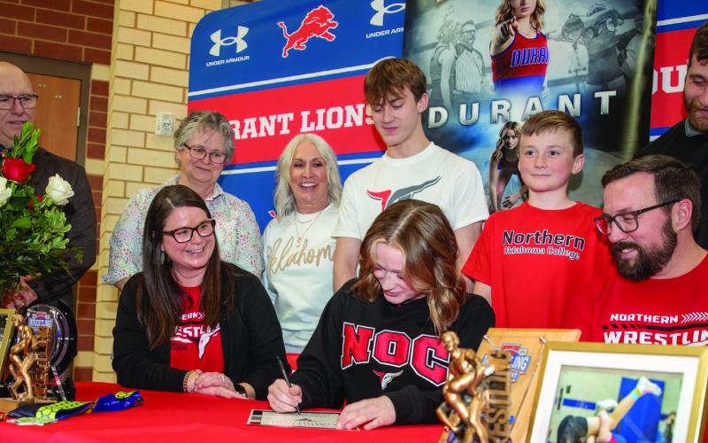 Durant Lady Lion Addison Polk signed to wrestle at Northern Oklahoma College and she is the first female athlete in school history to take wrestling to the college level. Shown sitting are her mother Kelley Polk and father Chaz Polk. Standing are DHS head wrestling coach Jim Taylor, Addison’s grandmothers Bonnie Eastwood and Pam Polk, brothers Aiden Polk and Channing Polk, and NOC women’s wrestling coach Jayden Miller. Matt Swearengin | Durant Democrat