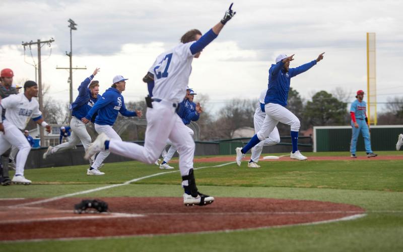 Southeastern baseball players run out onto the field after their victory Saturday against Newman University.