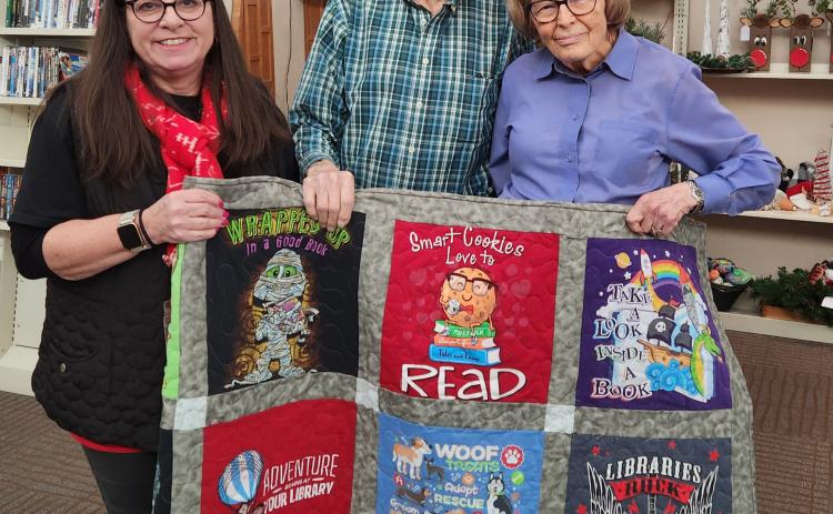 The quilt for the Friends of the Donald W. Reynolds Library Annual Holiday Craft Show was donated by the LuLu &amp; Hazel Quilt Shop, Durant. The winner of the T-Shirt quilt this year is Elbert and Marion Hill. Friends of the Library member Angie Mullen presented the quilt to Elbert &amp; Marion on December 10, 2025. Photo provided