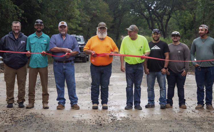 A ribbon was cut last week for a new bridge on Caney Creek Road south of Bushnell Corner and shown fourth from left is Bryan County District No. 2 Commissioner Justin Boone. Others shown include representatives of The Railroad Yard out of Stillwater that built the bridge. Matt Swearengin | Durant Democrat