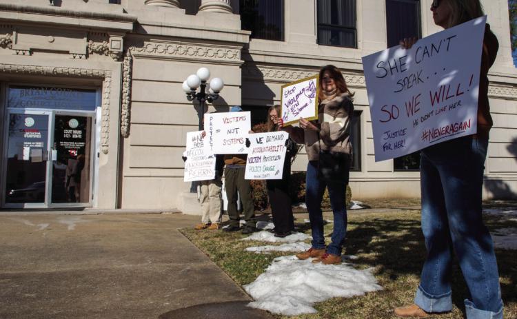 Protesters with the Bryan County Never Again Campaign held signs Monday outside of the courthouse. The protesters are seek-SEE ing changes to protect victims of domestic violence. Matt Swearengin | Durant Democrat