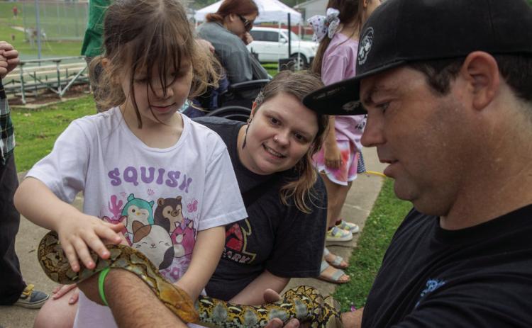 Chris Rauh of Snakes, Reptiles and Oddities, shows Cori Cox and Sovereign Smith a snake during the Durant Sustainability Coalition Earth Day Festival last Saturday at Rocket Park. Matt Swearengin | Durant Democrat