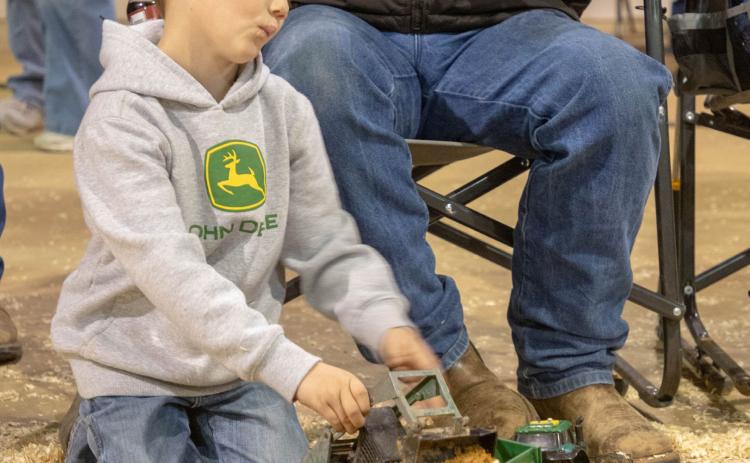 Lucas McKinney plays with his John Deere toys at the recent Bryan County Junior Livestock Show and Premium Sale Matt Swearengin | Durant Democrat