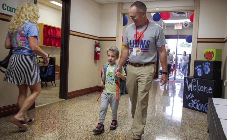 Durant Schools Superintendent Mark Moring escorts Christopher Norman to class at Robert E. Lee Early Childhood Center Monday morning. Matt Swearengin | Durant Democrat