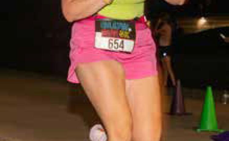Spencer Harvey checks her time as she crosses the finish line during the Feedling Hope 5K run Friday evening.
