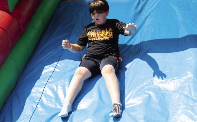 R.J. Minniefield goes down a slide on a bounce house during The Mission’s second-annual Summer Bash Saturday at Carl Albert Park. Matt Swearengin | Durant Democrat