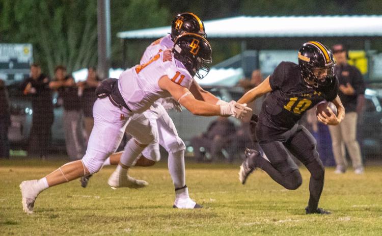 Caddo Bruin quarterback Cale Wigington runs down field in the game with the Dewar Dragons. Also shown is Dragon Peyton Kilhoffer. Matt Swearengin | Durant Democrat