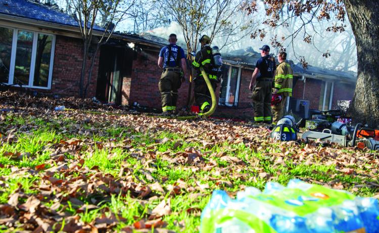 Firefighters spray water onto the roof of a home that burned last week on Marie Drive. Matt Swearengin | Durant Democrat