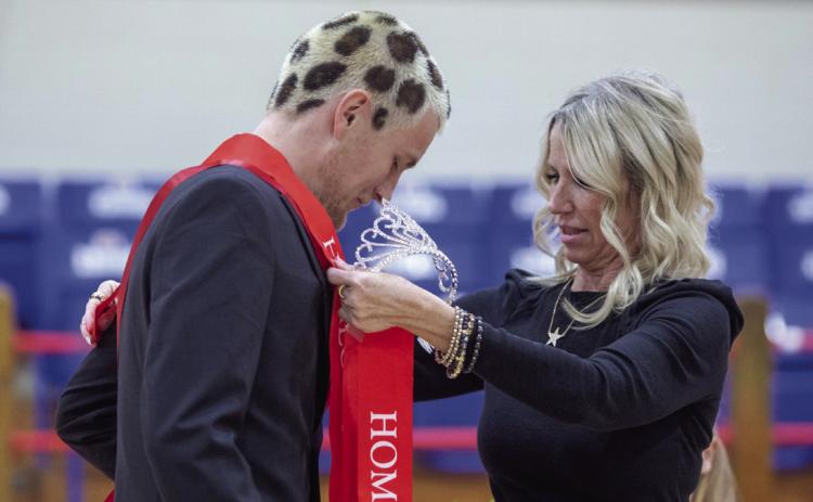 Silo Schools teacher and cheer coach Mishael Metheny presents Lewis Cross a sash after he was named Homecoming King.
