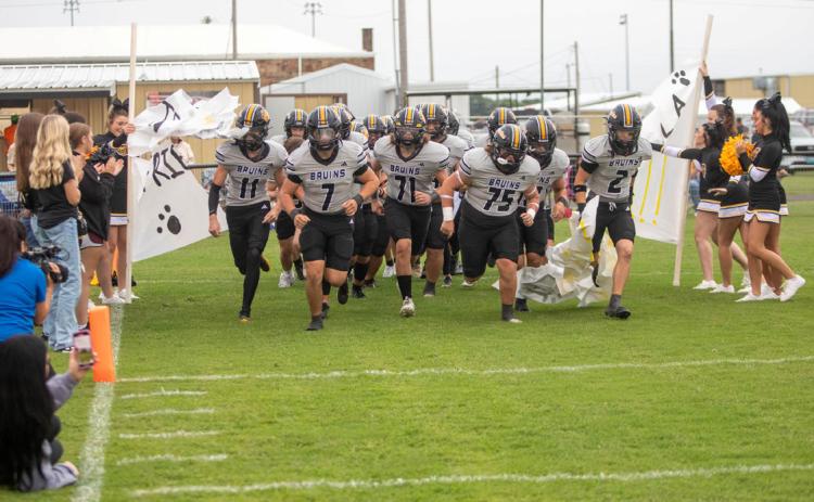 Caddo Bruins crash through a paper banner during a home game. Matt Swearengin | Durant Democrat