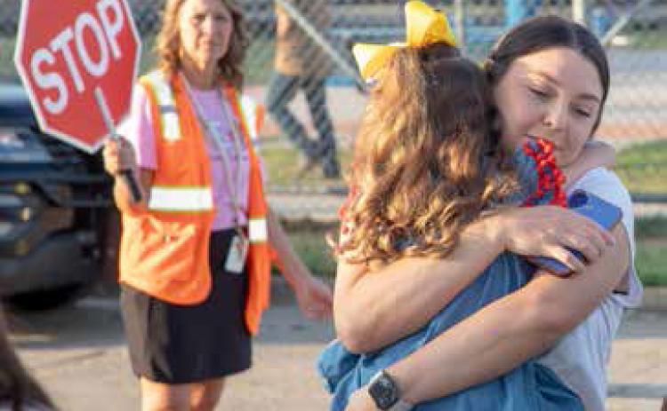 A child is embraced before the start of school Aug. 17 at the Robert E. Lee Early Childhood Center. In the back is REL principal Lisa Whitley.