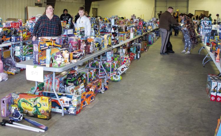 Toys filled Haggard Hall at the fairgrounds during the Marine Corps Reserves Toys for Tots/Durant Lions Club Lions Toy Box toy giveaway Dec. 20. Oklahoma Highway Patrol Trooper Chris Smith, right, was among the many volunteers helping with the event. Matt Swearengin | Durant Democrat