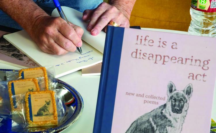 Durant poet Ron Wallace signs a copy of his poetry book, “Life is a Disappearing Act,” at a recent signing event at Sundrop books in downtown Durant. Matt Swearengin | Durant Democrat