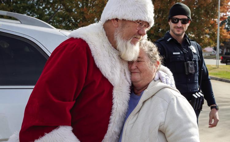 Judy Holland embraces Santa Claus after she was pulled over by Durant Police and given toys and food as part of DPD’s Santa Stops. Matt Swearengin | Durant Democrat