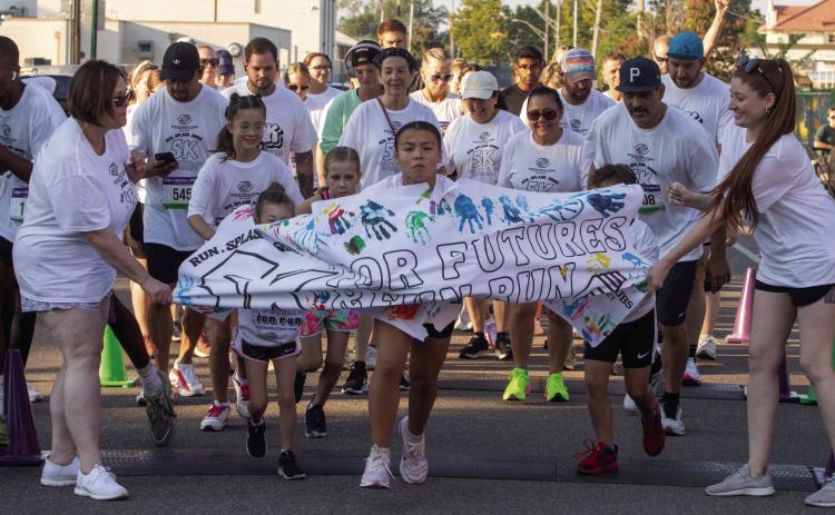 Runners during the Boys &amp; Girls Club Color Run crash through a paper banner at the start of the race Saturday morning. Matt Swearengin | Durant Democrat