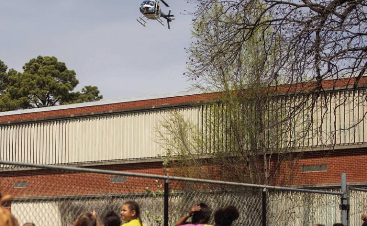 LEFT: Children at the Boys &amp; Girls Club watch as the helicopter arrives to drop Easter candy.