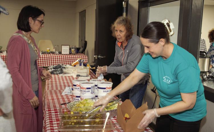 RSVP volunteer Carolyn Dills and Sheri Schulze, executive director of RSVP, serve nachos to Hiley Johnson during a recent fundraiser for RSVP. Matt Swearengin | Durant Democrat