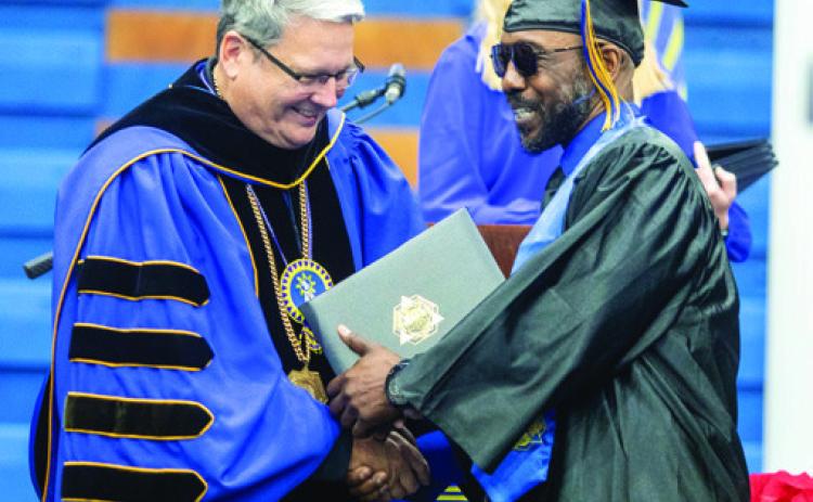 Matt Swearengin | Durant Democrat Southeastern Oklahoma State University President Thomas Newsom presents a baccalaureate degree to a graduate during commencement last Saturday morning at Bloomer Sullivan Arena.