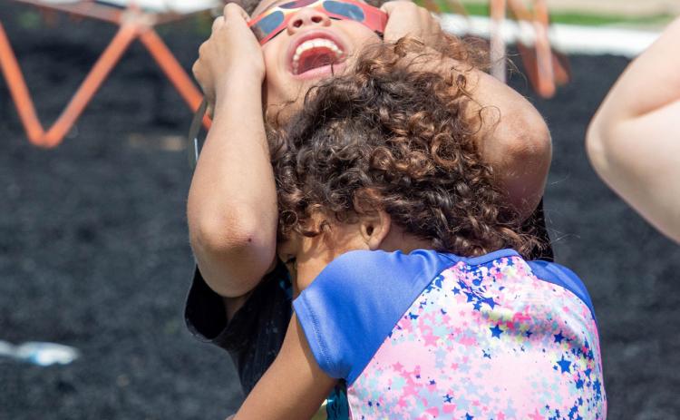 The Boys &amp; Girls Club had an eclipse viewing party and Beckham St. Clair gazes skyward at the eclipse while being embraced by Lyllian Richardson. Matt Swearengin | Durant Democrat
